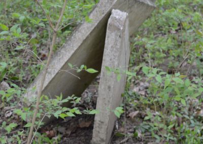 headstones leaning against one another in an abandoned cemetery