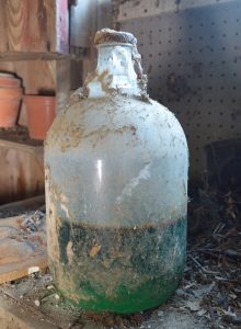 large glass jar with green inside and spider webs