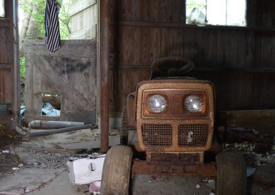 riding lawn mower with round headlights in an abandoned barn