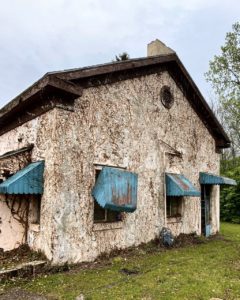 side of abandoned building with green awning and ivy